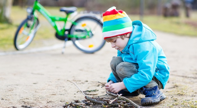 Boy with his bike plays with sticks