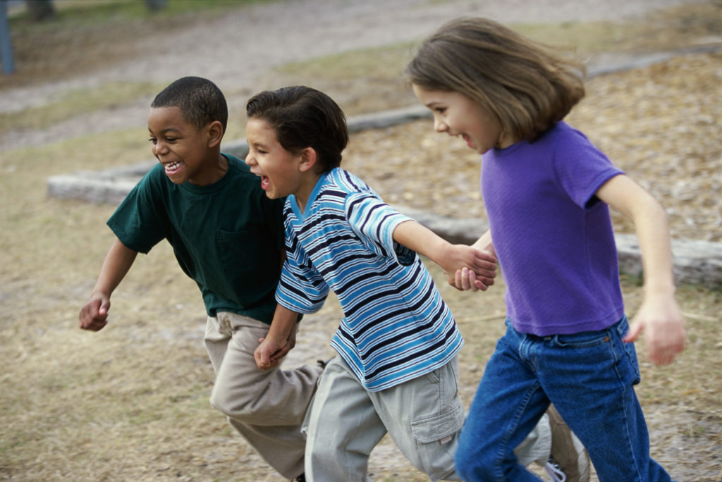 Children running on a playground holding hands