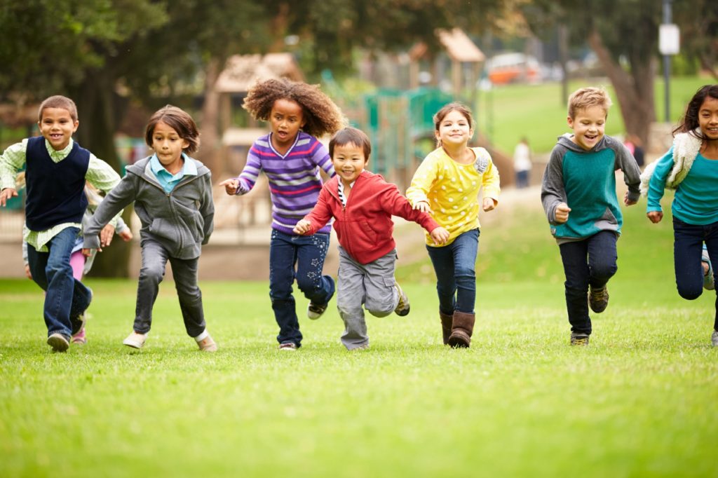 Children running outside holding hands in a line