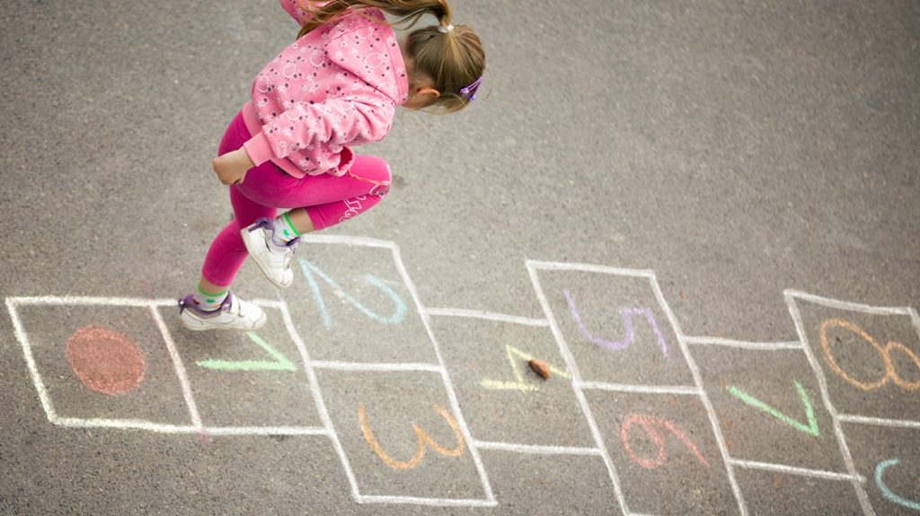 Young girl plays hopscotch