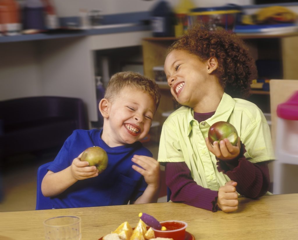 Kids eating apples and laughing
