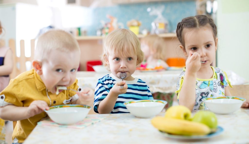 Preschool children eating cereal at the table