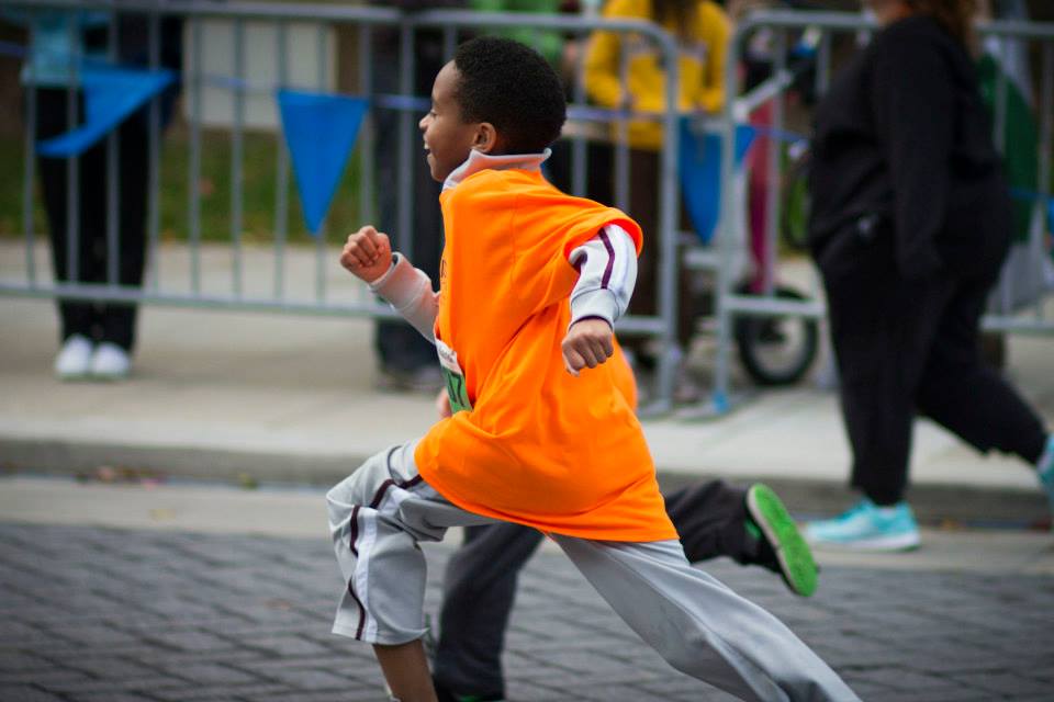 A young child smiles as he nears the finish line at the Monumental Kids run
