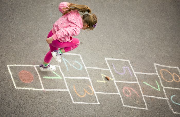 Girl plays hopscotch outside on the playground