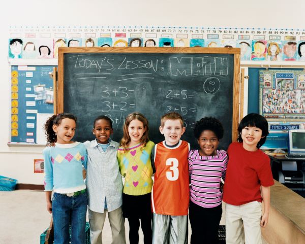 Children in school standing in front of a chalkboard