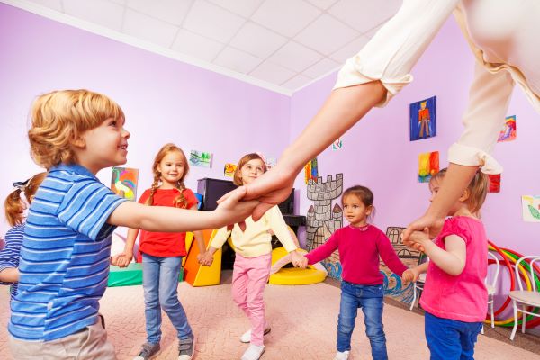 Children play with their caregiver in a child care room
