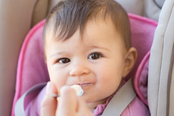 Baby being fed yogurt on a spoon