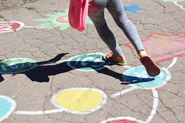 Girl runs in flip flops on sunny, painted sidewalk
