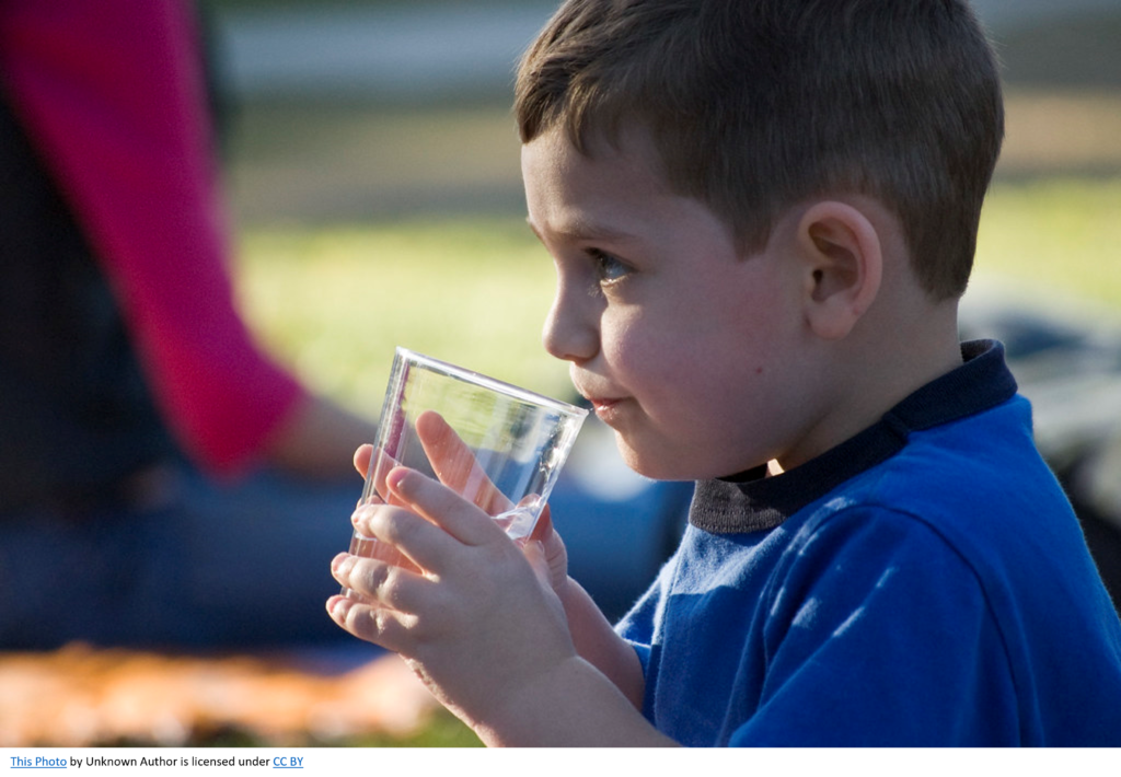 A young boy drinking a glass of water