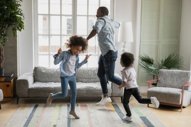 Family joyfully dancing indoors in the living room